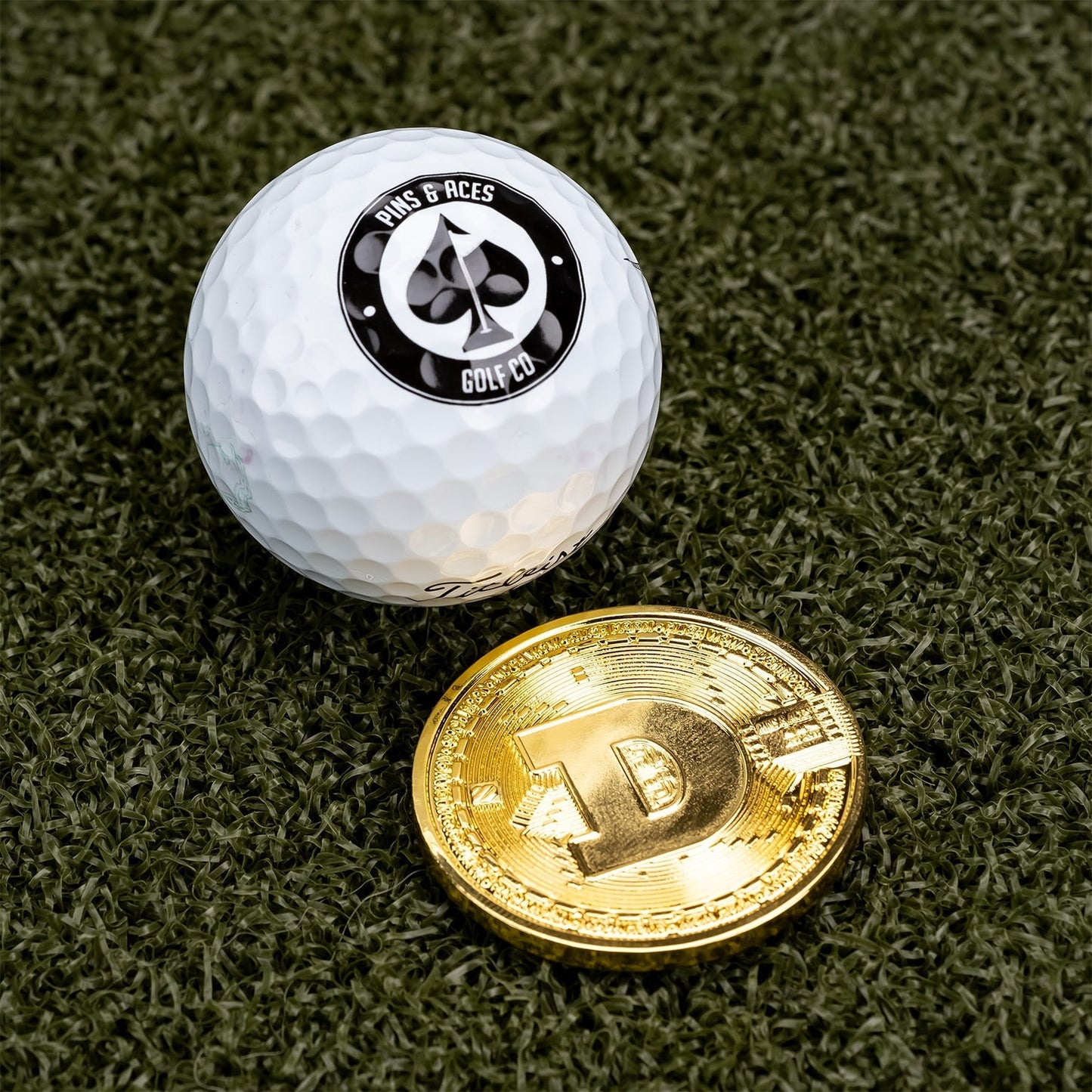 Dogecoin ball marker next to a golf ball, featuring a bold design for stylish golfing accessories.