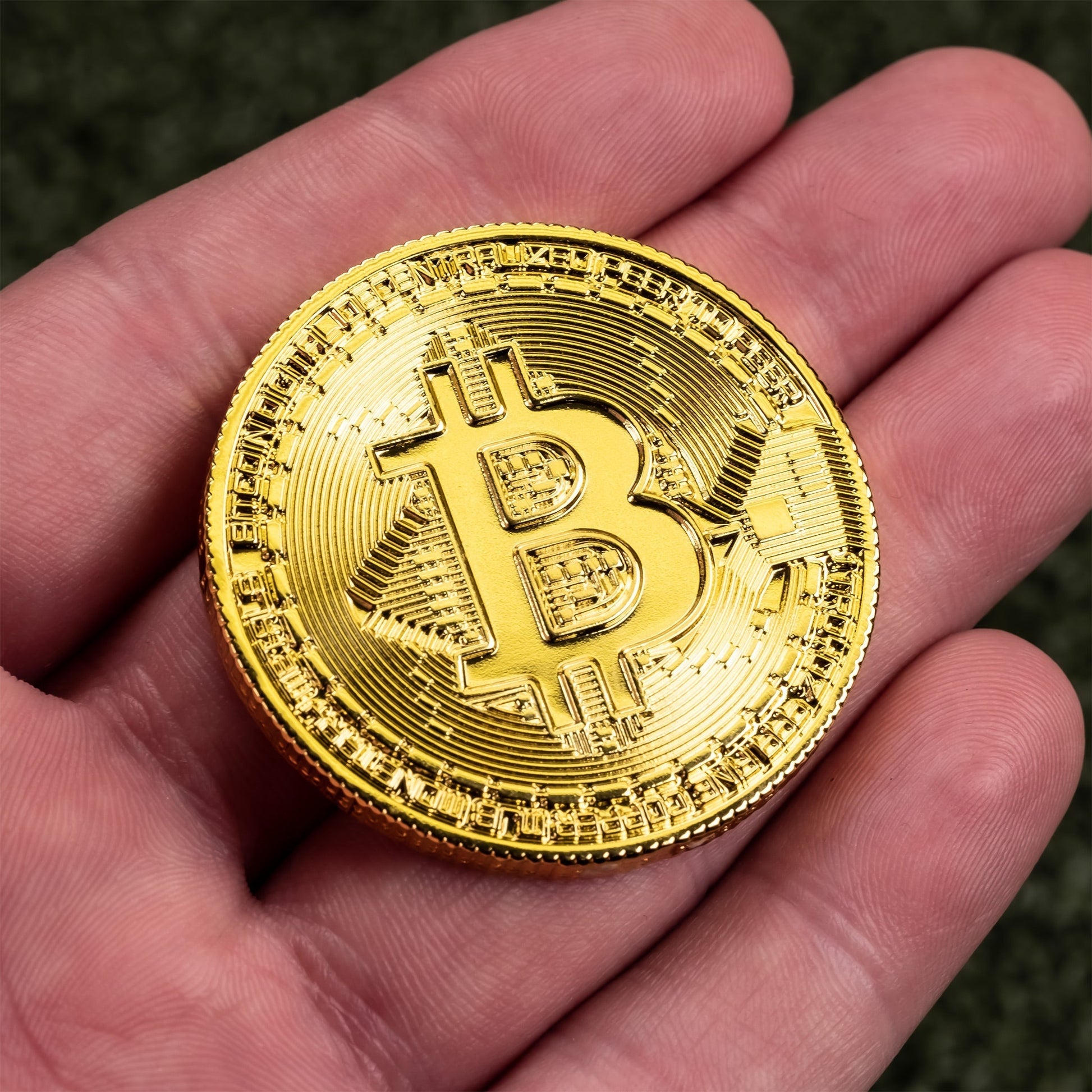 Gold Bitcoin ball marker held in a hand, featuring intricate detailing and the iconic Bitcoin logo for golfers.