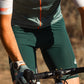 Person riding a bicycle with focus on green shorts and handlebar