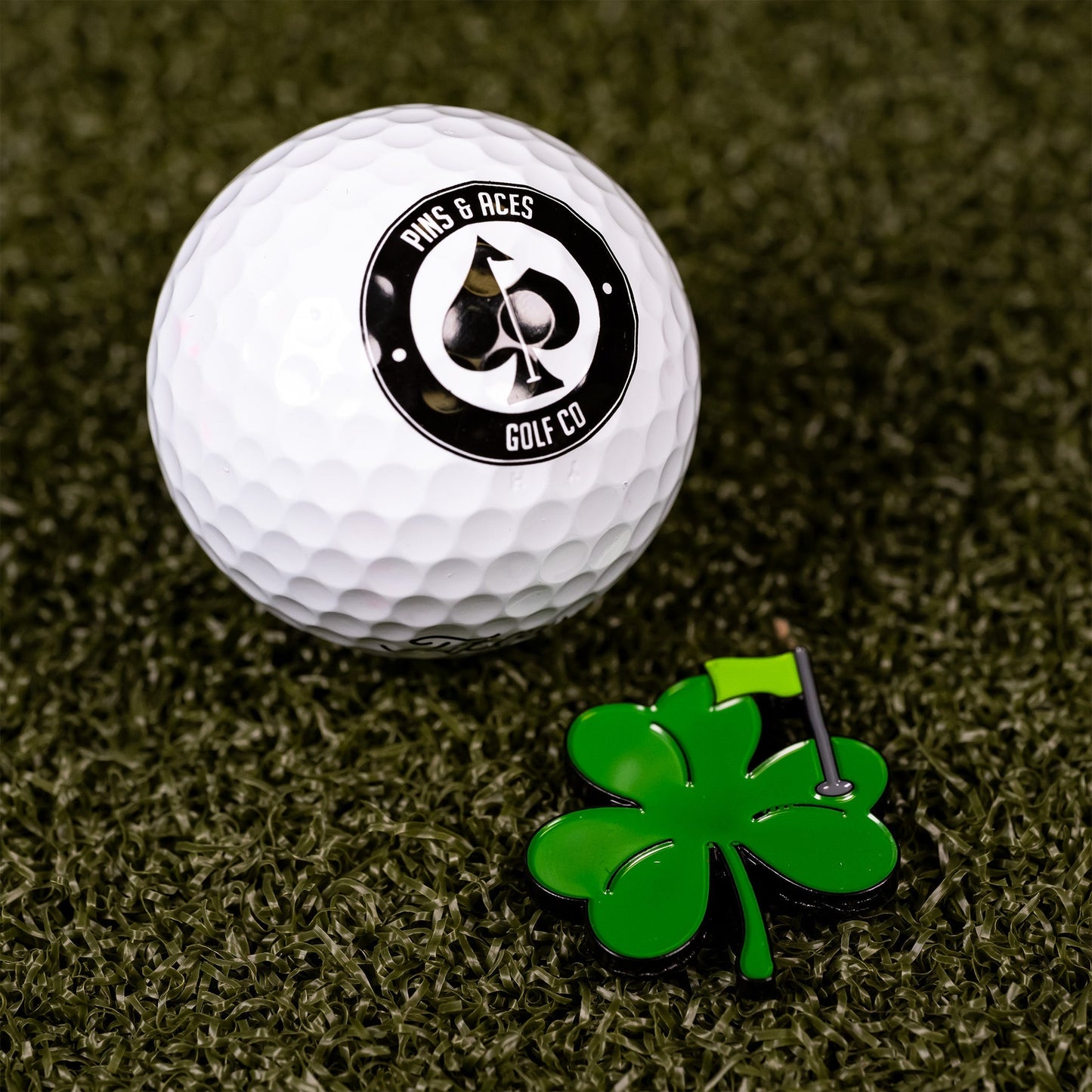 Shamrock ball marker with a green clover design next to a white golf ball.