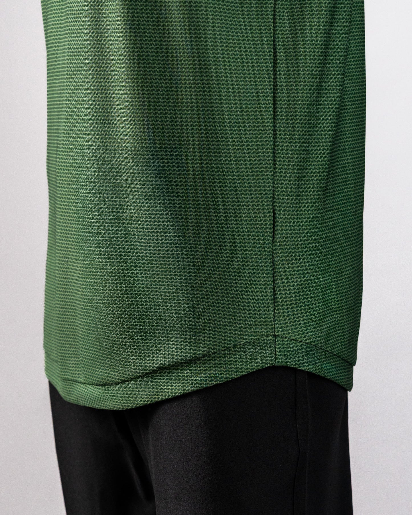 Close-up of a green Player Preferred™ Polo shirt with a forest wave pattern, paired with black pants.