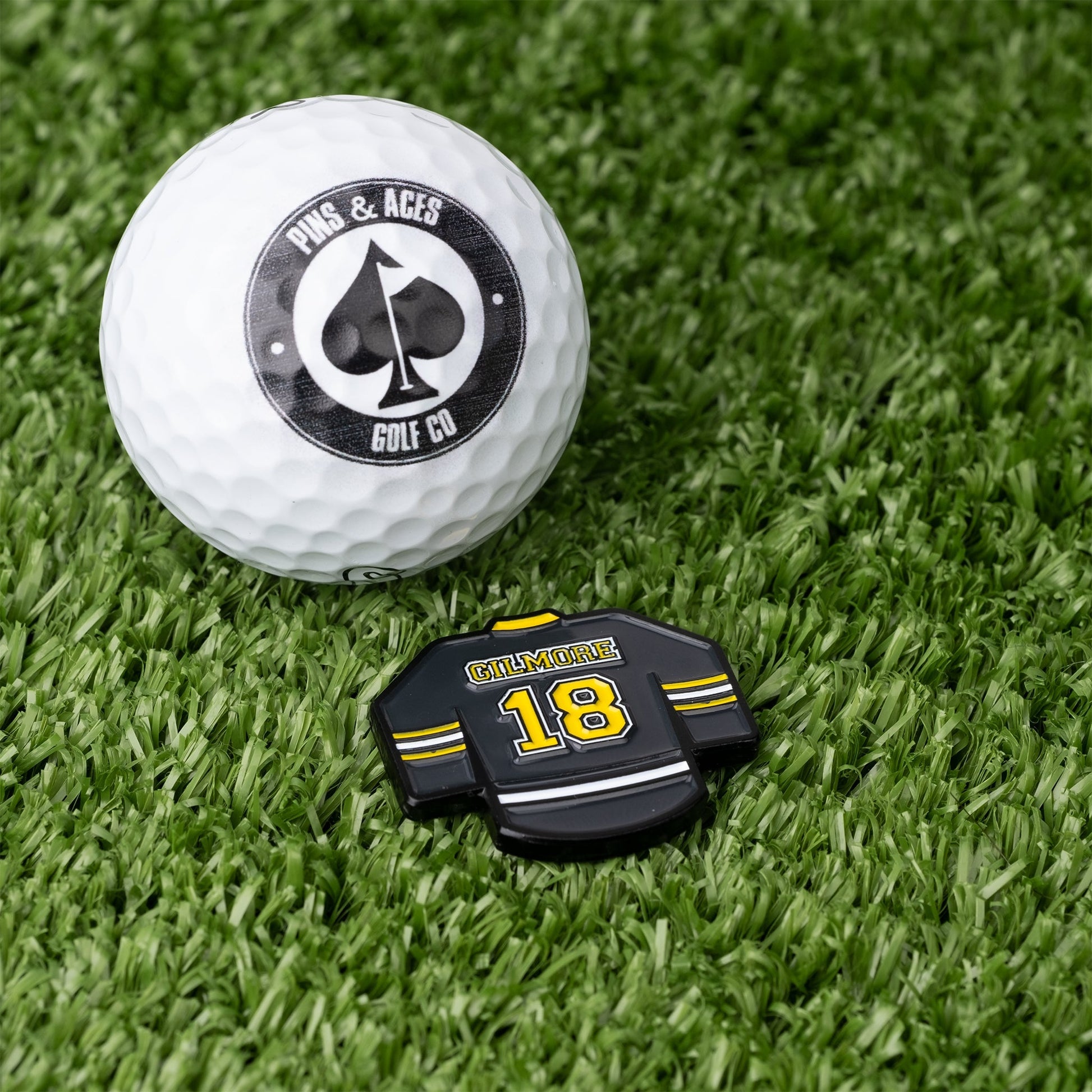 Gilmore Jersey Ball Marker beside a golf ball on a green surface.