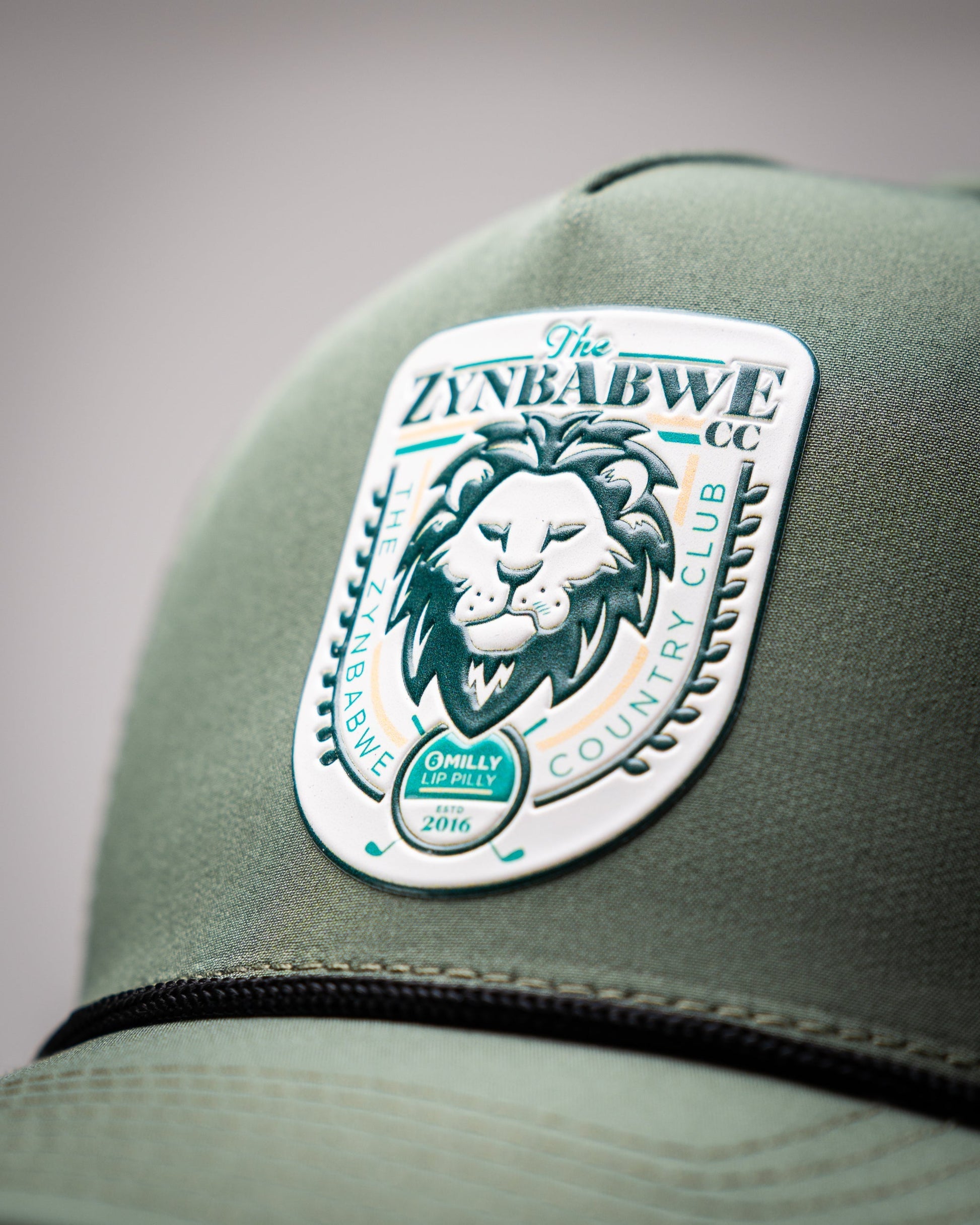 Olive perforated rope hat with Zynbabwe Country Club logo, featuring a snapback closure.