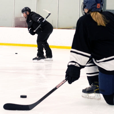 Two ice hockey players on an indoor rink with one player in action.