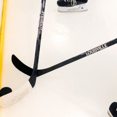 Two hockey sticks with 'Louisville' branding on a white background