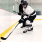 Two ice hockey players on an indoor rink with one player in a white jersey and black helmet, the other in a black jersey and helmet.