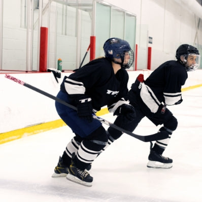 Two ice hockey players in action on an indoor ice rink.