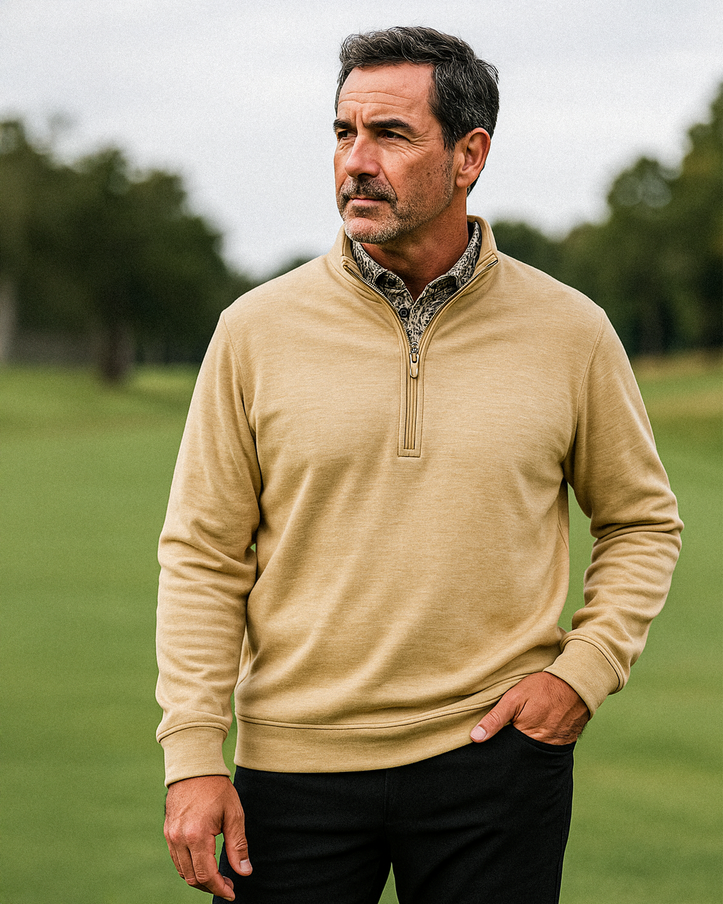 Man wearing a tan Player Preferred™ Pullover in Sand with a quarter-zip, standing outdoors on a golf course.