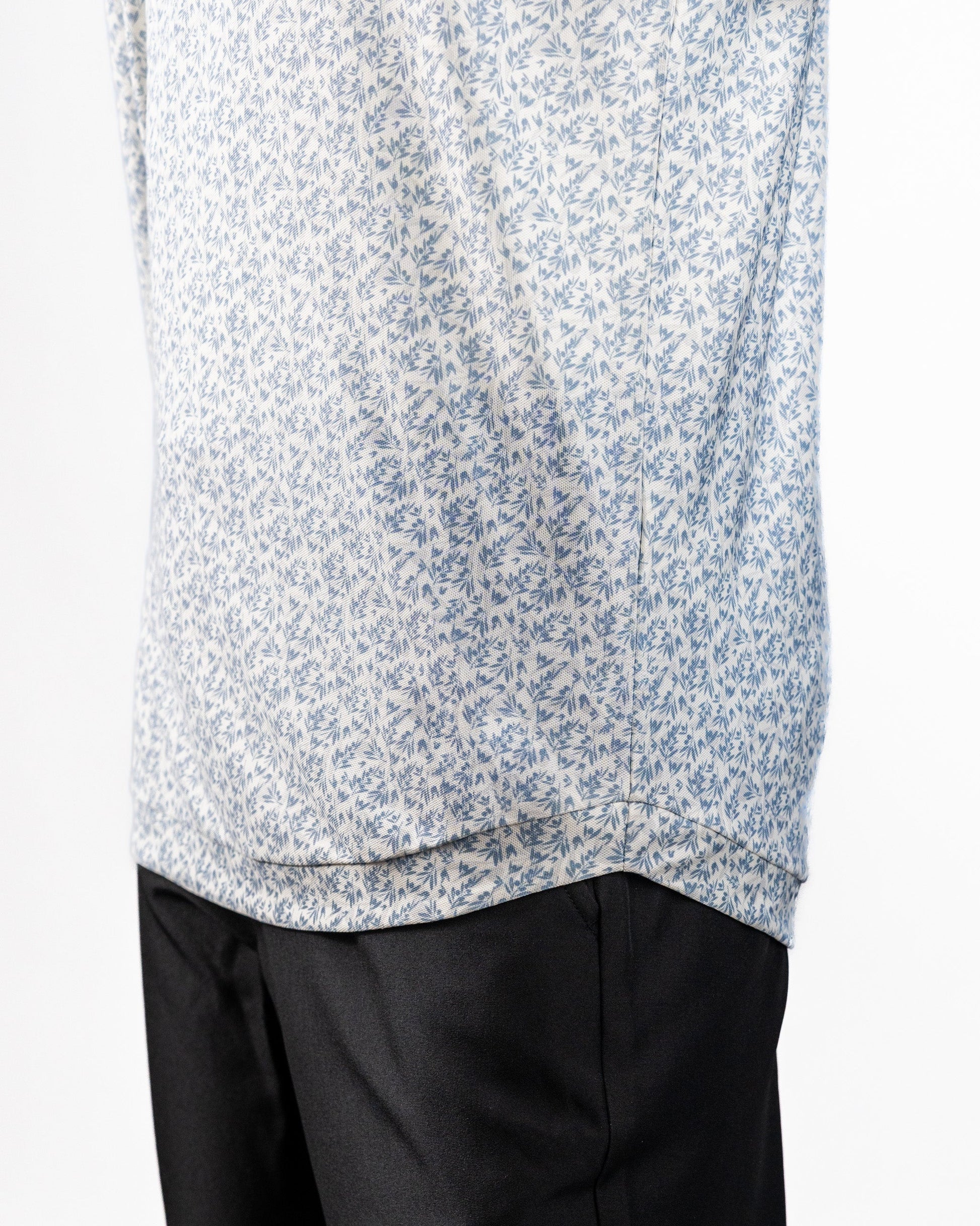 Close-up of a Player Preferred™ Polo in olive grove with a small blue floral pattern, paired with black pants.