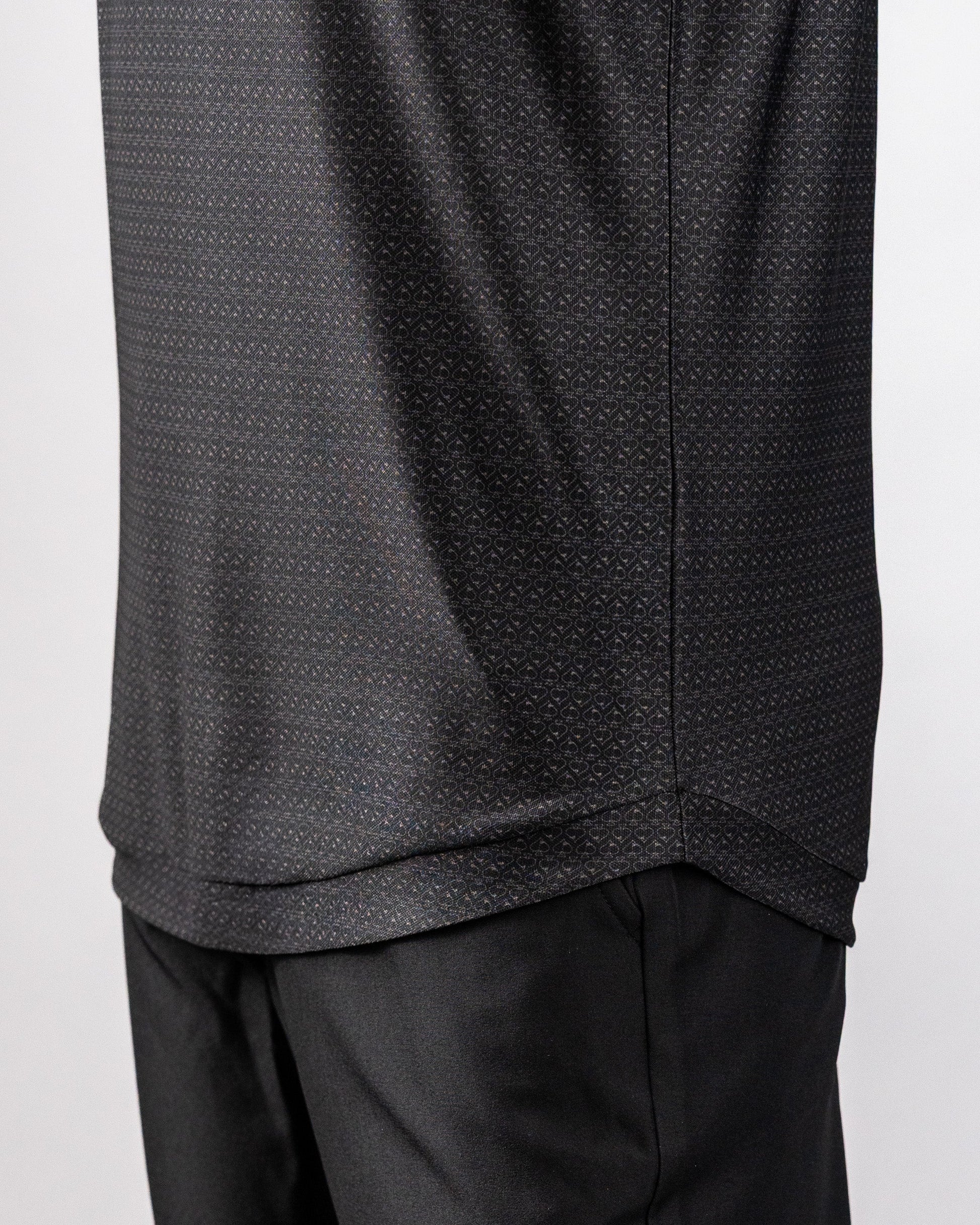 Close-up of a black polo shirt with a subtle, intricate pattern, paired with black pants, showcasing a stylish, modern look.