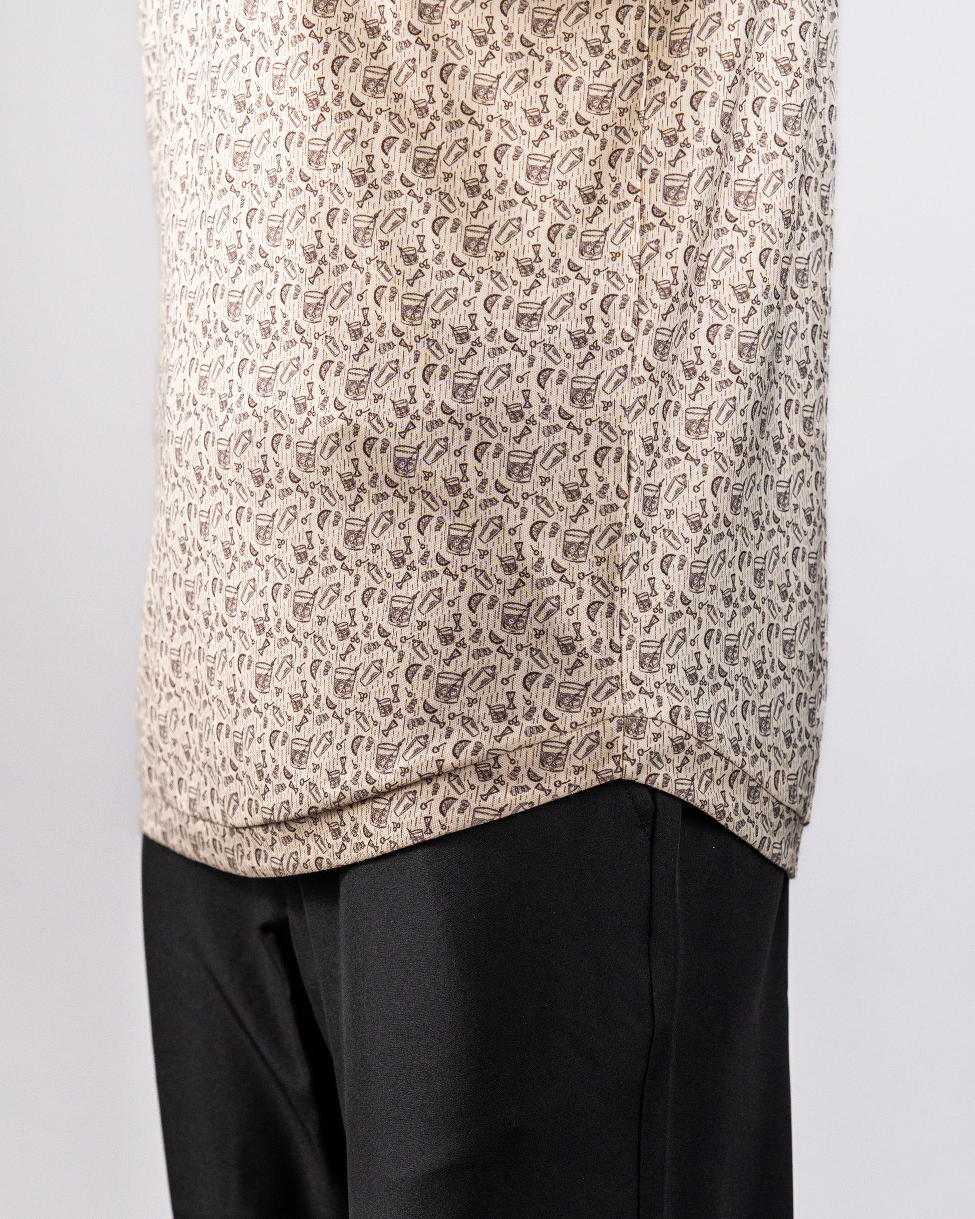 Close-up of a beige Player Preferred™ Polo with a small, dark geometric pattern, paired with black pants.