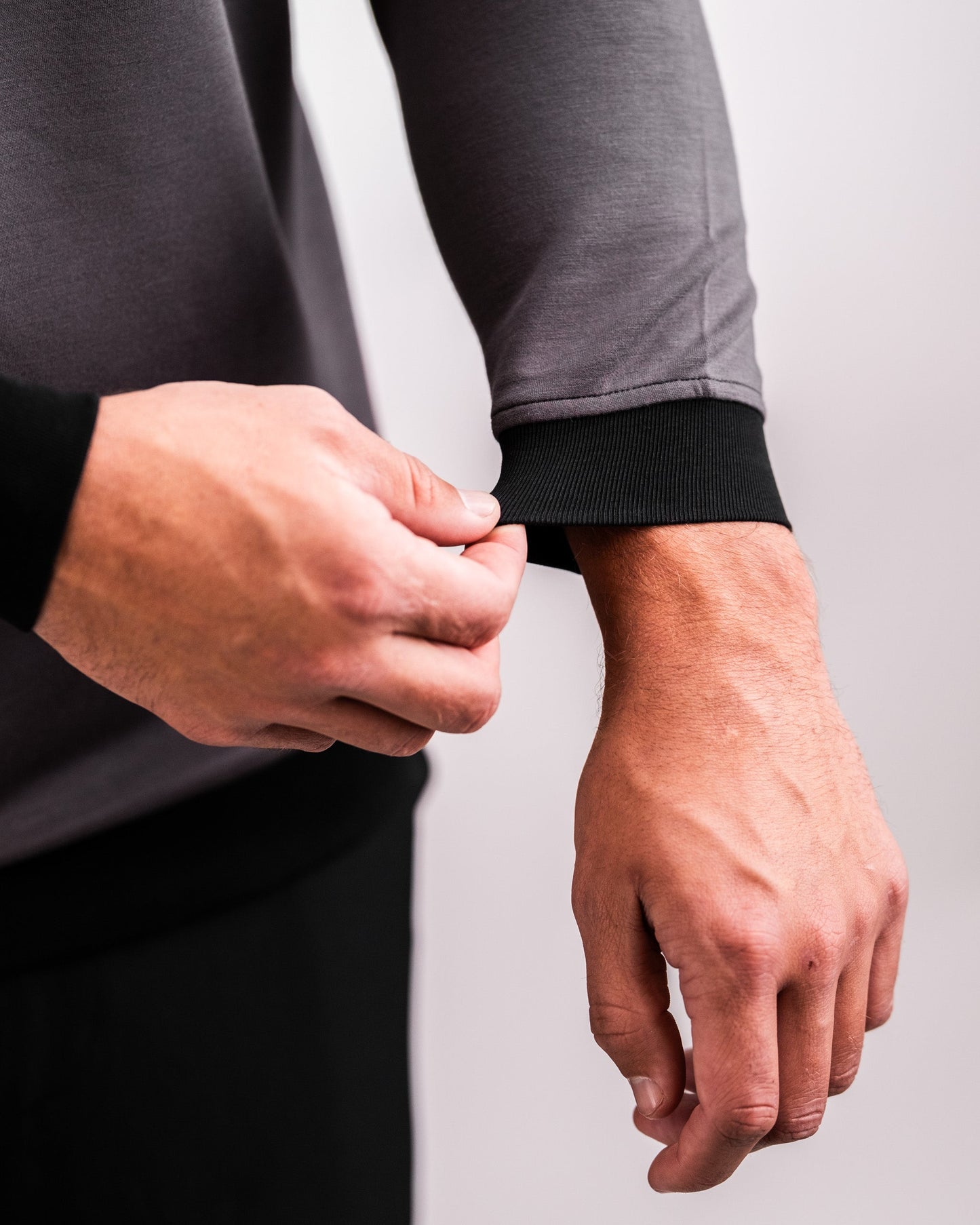 Close-up of a person adjusting the cuff of a slate grey Player Preferred™ Crewneck sweatshirt with black ribbed cuffs.