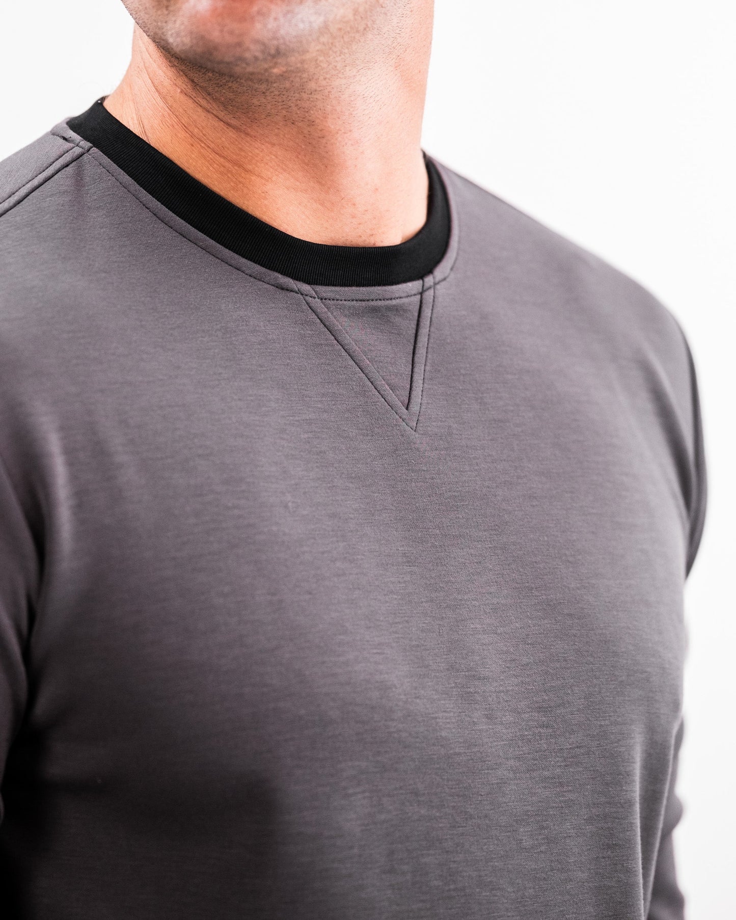 Close-up of a man wearing a slate grey Player Preferred™ crewneck with black collar trim, highlighting the fabric and stitching details.