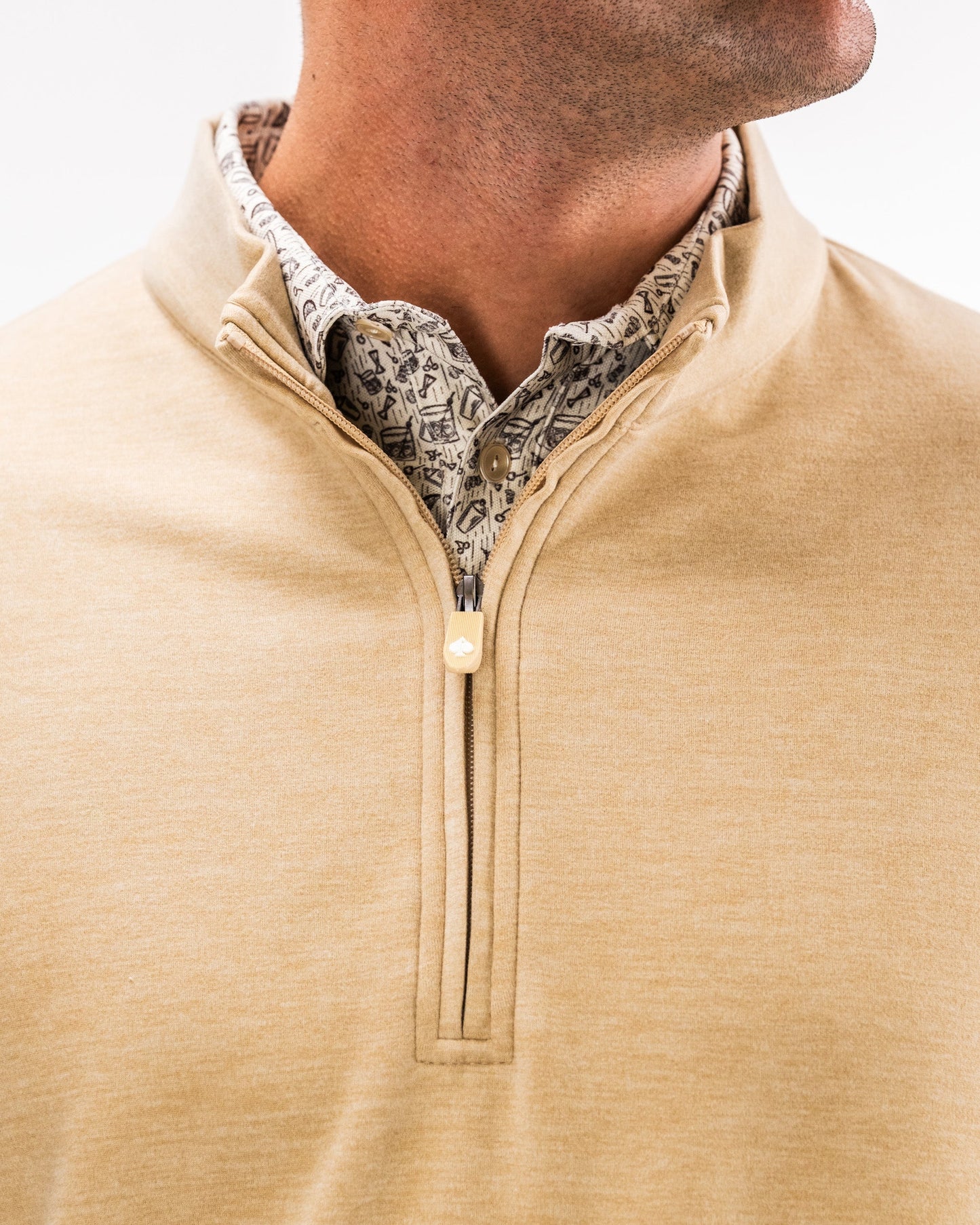 Close-up of a man wearing a sand-colored Player Preferred™ Pullover with a zip front, layered over a patterned button-up shirt.