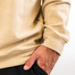 Close-up of a person wearing a beige Player Preferred™ Pullover in sand color, with hand in pocket, showcasing casual style and fabric texture.