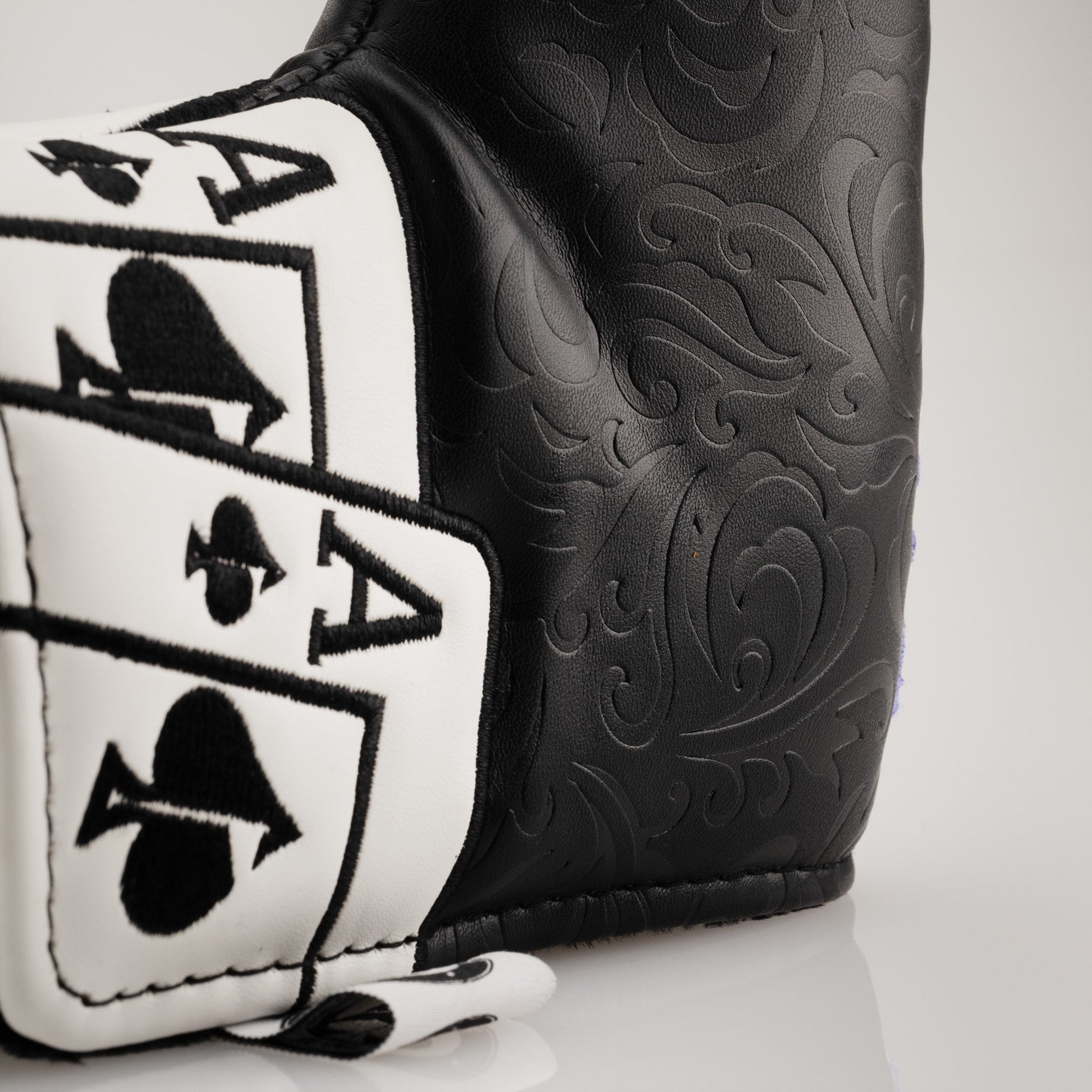 Close-up image of an Ace of Spades blade putter cover, featuring intricate embossed patterns on black faux leather with a prominent black and white Ace of Spades card design.