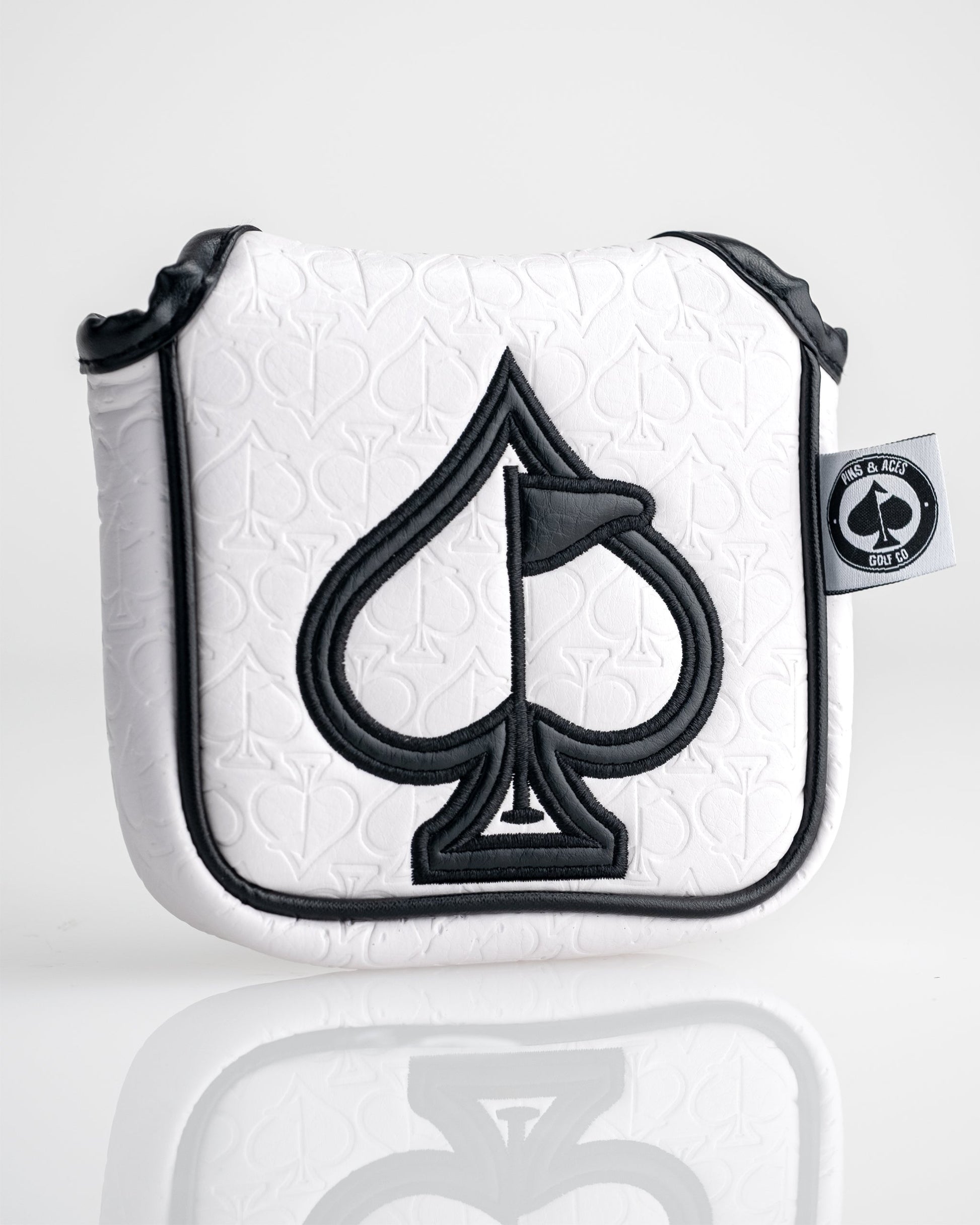 White golf headcover with embossed spade pattern, black embroidered spade logo, black trim, and a small black and white "P...