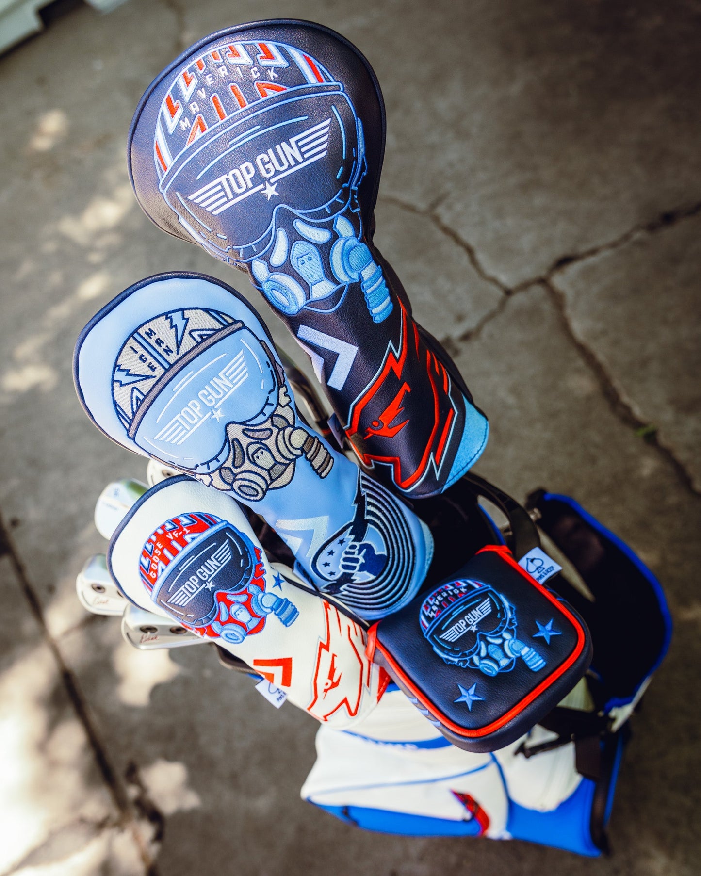 Set of four Top Gun Maverick themed golf club headcovers featuring fighter pilot helmet designs in red, white, blue, and black colors.