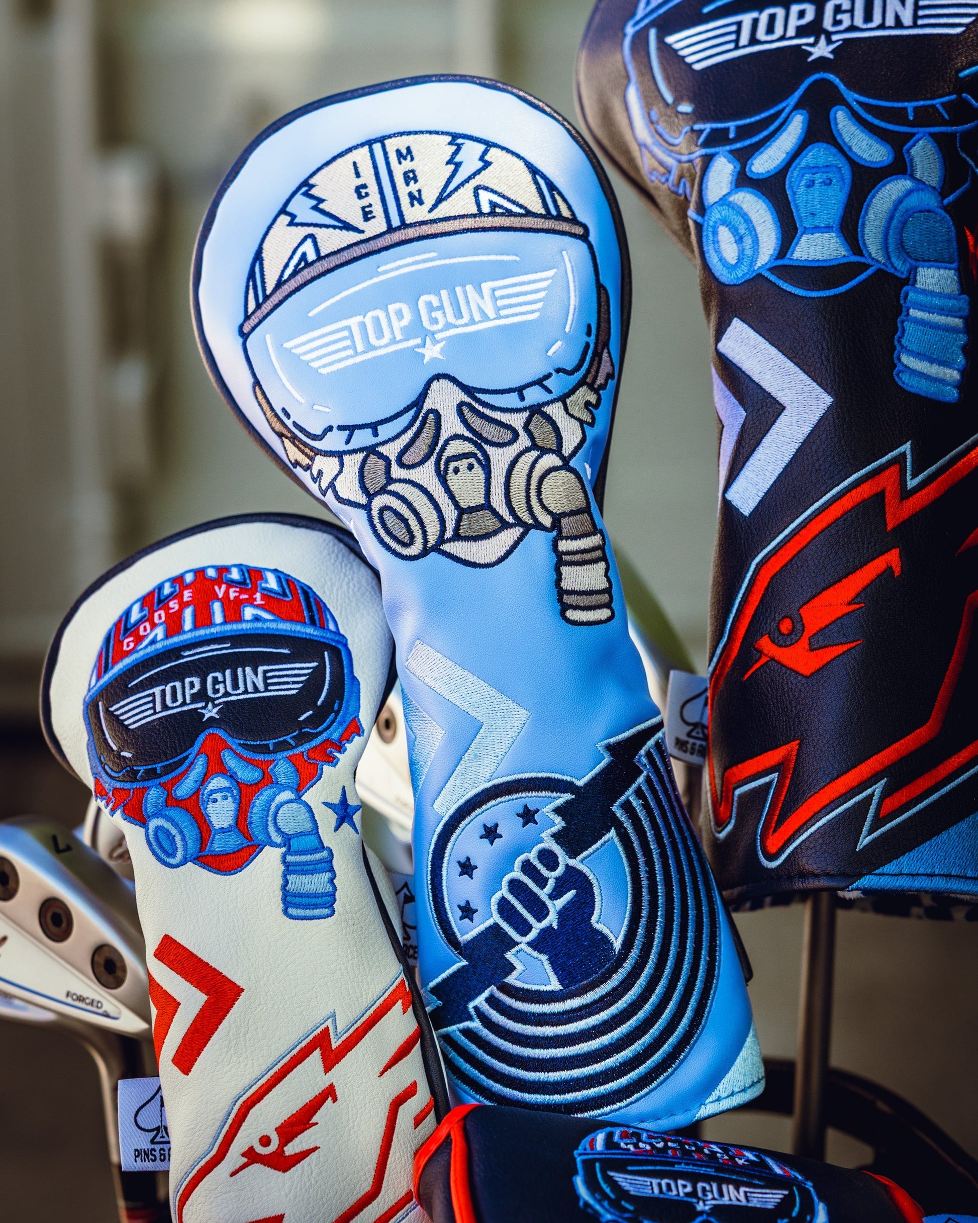 Set of Top Gun Ice Man themed golf headcovers featuring fighter pilot helmet designs in blue, white, red, and black colors.
