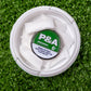 Alt text: "Top view of a 6 Milly Spearmint Ball Marker in a white container with individual pouches, placed on artificial green grass. The container label shows 'P&A, Spearmint, 6 mg'."
